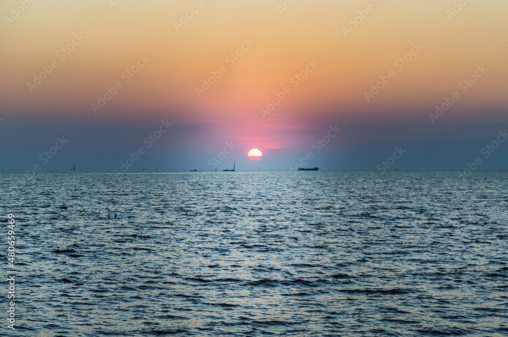 Obraz premium Beautiful sunset over a calm sea with a blue and orange glowing sky. Space for text, Selective focus.