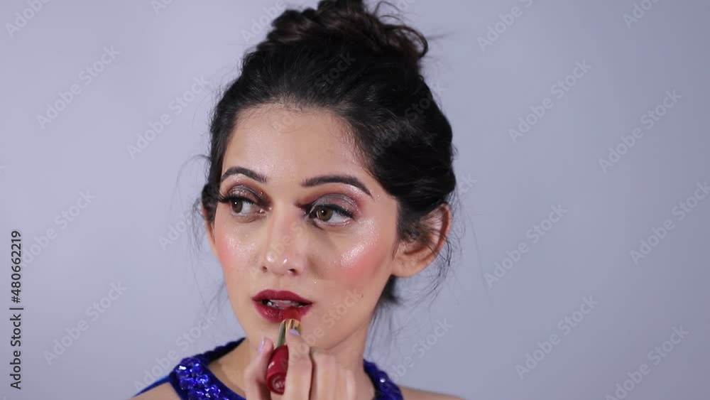 Fashion Model applying red lipstick on grey background With Moody wearing blue dress Sexy Woman Indian Fashion Model applying red lipstick on grey background With Moody wearing blue dress Sexy Woman Indian