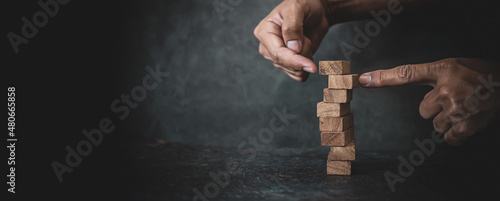 Hand prevent wooden block stack not to fall concept of safety and prevention collapse or crash of financial business and risk management or strategic planning and insurance.