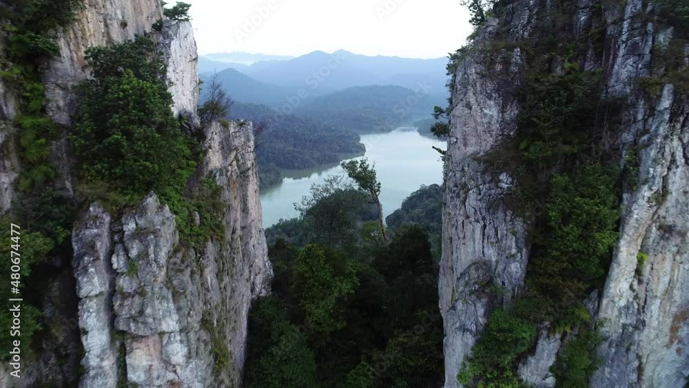 Aerial view of forest in Malaysia at sunrise. Drone shot flying through the opening of huge naturally formed quartz ridge. Nature background footage in 4K resolution Aerial view of forest in Malaysia at sunrise. Drone shot flying through the opening of huge naturally formed quartz ridge. Nature background footage in 4K resolution
