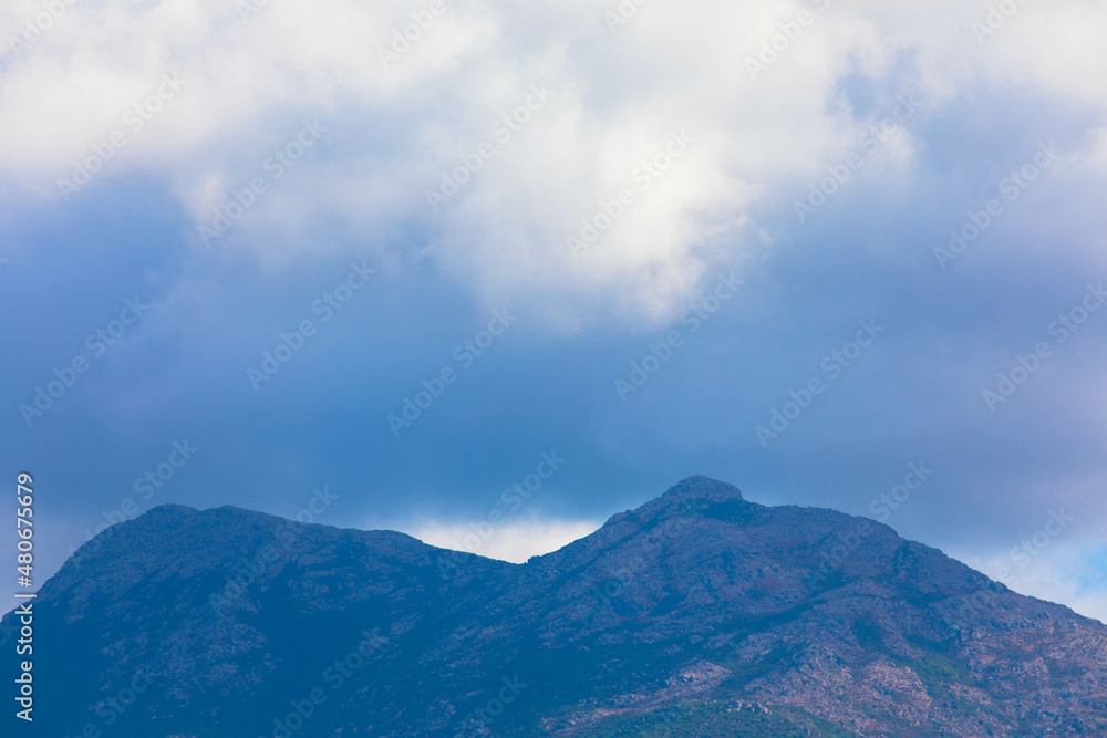 Panoramic view of impressive rock formations in the Mediterranean landscape of the Bavella mountains. Many dark rain clouds hang over the mountain peak. Corsica, France. Place for text.