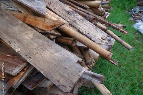 Photo Illustration of Semi-Finished Building and Remaining Building Materials Such as Wood, Bamboo, Barn, Tile Roof, Sand. Everything is placed on the Grasslands