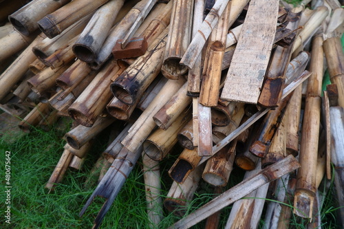Photo Illustration of Semi-Finished Building and Remaining Building Materials Such as Wood, Bamboo, Barn, Tile Roof, Sand. Everything is placed on the Grasslands