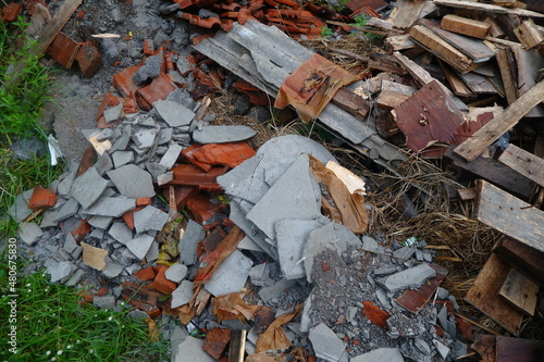 Photo Illustration of Semi-Finished Building and Remaining Building Materials Such as Wood, Bamboo, Barn, Tile Roof, Sand. Everything is placed on the Grasslands
