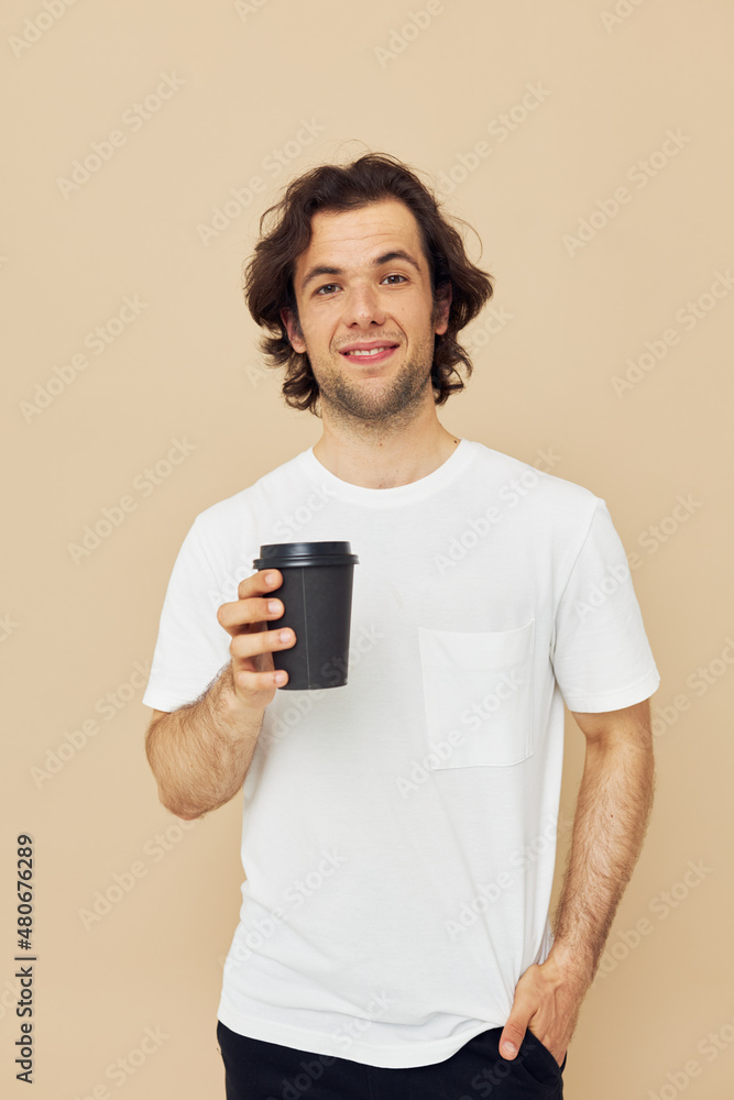 handsome man in a white T-shirt with a black glass in hand Lifestyle unaltered handsome man in a white T-shirt with a black glass in hand Lifestyle unaltered
