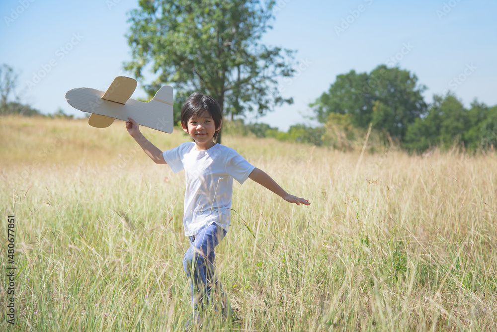 Asian child playing cardboard airplane in the meadow Asian child playing cardboard airplane in the meadow