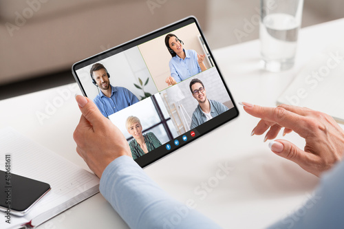 Woman Using Digital Tablet For Video Conference With Group Of Business People