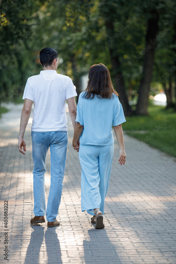 Man and woman walking along a path in a summer park.