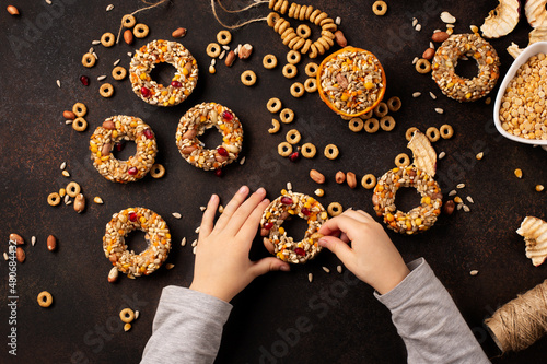 Small child making homemade birdseed dumplings. Winter food for birds on dark wooden background, top view photo