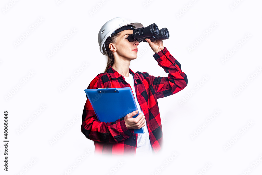 Young woman in construction clothes with clipboard looks through binoculars on a light background. Young woman in construction clothes with clipboard looks through binoculars on a light background.