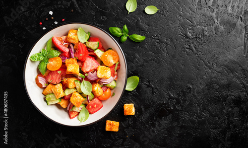 Tuscan Panzanella, traditional Italian salad with tomatoes and toasted bread. Vegetarian panzanella salad.Black background. Top view 