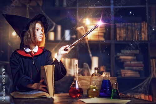 Canvas Print little witch makes a spell with a magic wand