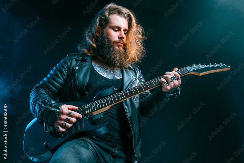 Obraz premium Guitar player. Rockstar bearded man plays on electric guitar isolated on black background.