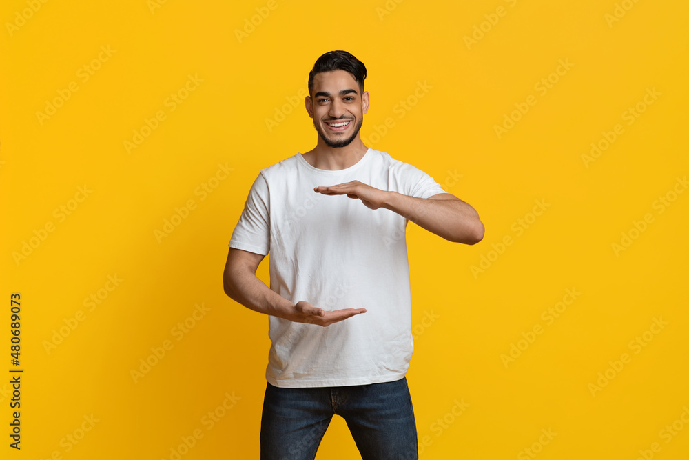 Positive muslim guy holding something invisible in his hands Positive muslim guy holding something invisible in his hands