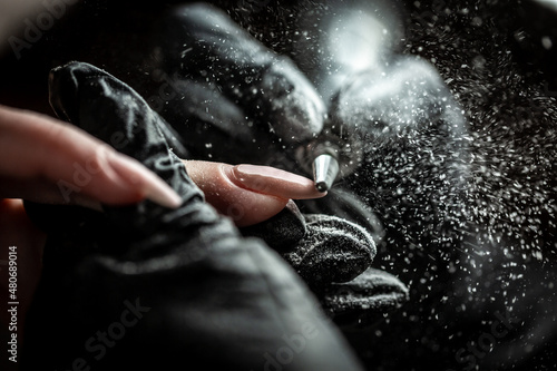 Papier peint Manicurist is applying electric nail file drill to manicure on female fingers