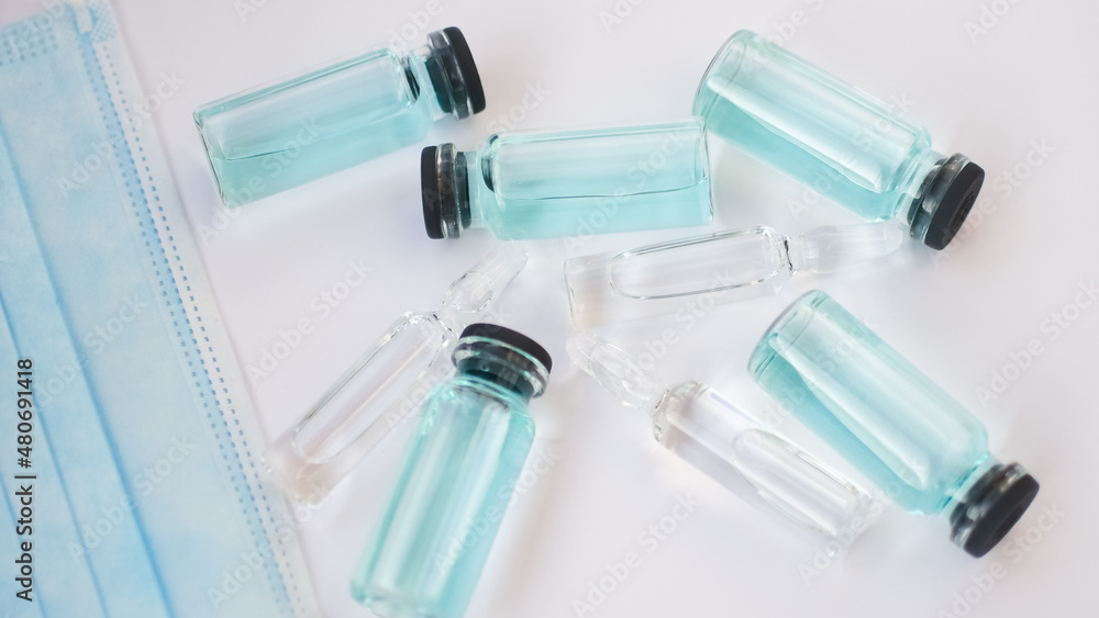 Vial vaccine, top view of glass ampoules with transparent and blue liquid lying on white background, global vaccination concept Vial vaccine, top view of glass ampoules with transparent and blue liquid lying on white background, global vaccination concept