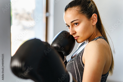 Young female boxer punching heavy bag - woman in boxing gloves training © Miljan Živković