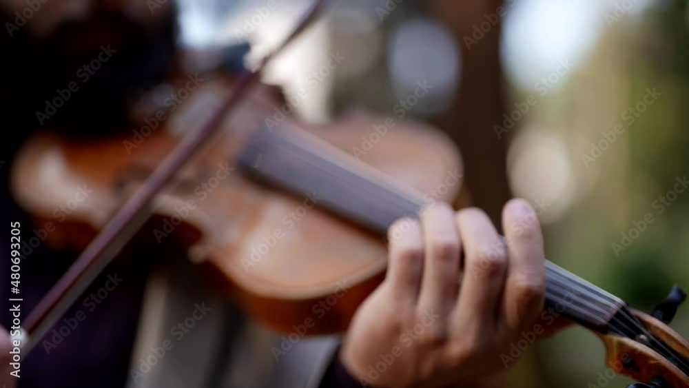 Close-up of a hand and a musical instrument a street musician, a classical violinist playing a classical wooden violin. Close-up of a hand and a musical instrument a street musician, a classical violinist playing a classical wooden violin.