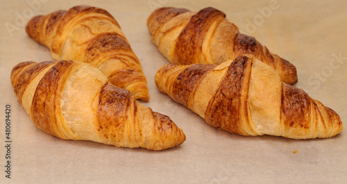 Croissants fresh from the oven on a parchment covered oven grill tray