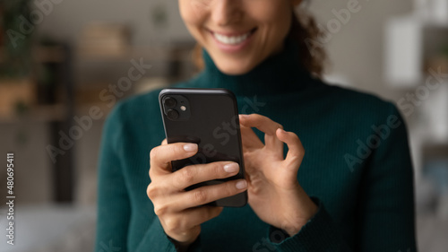 Close up young woman holding cellphone in hands, playing mobile games, shopping in internet store, web surfing information, communicating distantly, ordering food or taxi online, tech addiction.