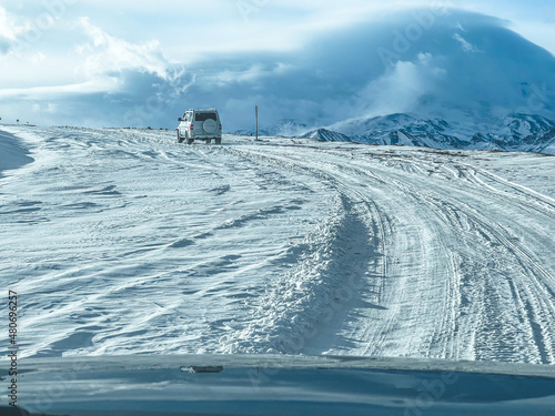 The SUV is driving on a snow-covered road in the mountains.