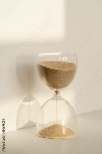 Transparent hourglass on a white sunny background.