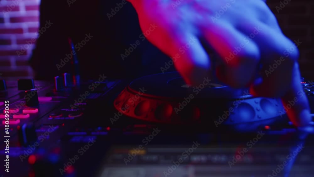 DJ works behind DJ station and presses buttons on fader. Male hand presses buttons and rotates platform on digital mixing console, closeup, front view. Concept of modern party in nightclub. DJ works behind DJ station and presses buttons on fader. Male hand presses buttons and rotates platform on digital mixing console, closeup, front view. Concept of modern party in nightclub.
