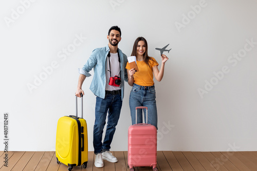 Travel abroad concept. Joyful couple ready for vacation, woman holding little plane model and flight tickets