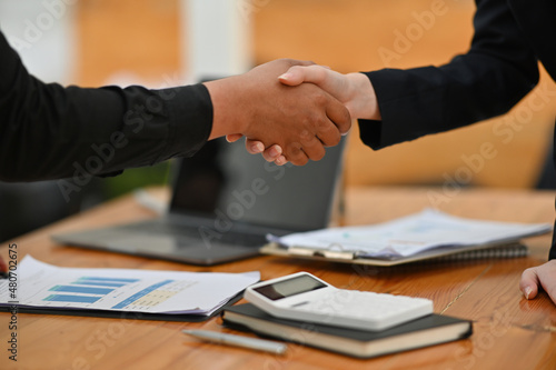 Foto Cropped image of businesspeople making a handshake at the business office