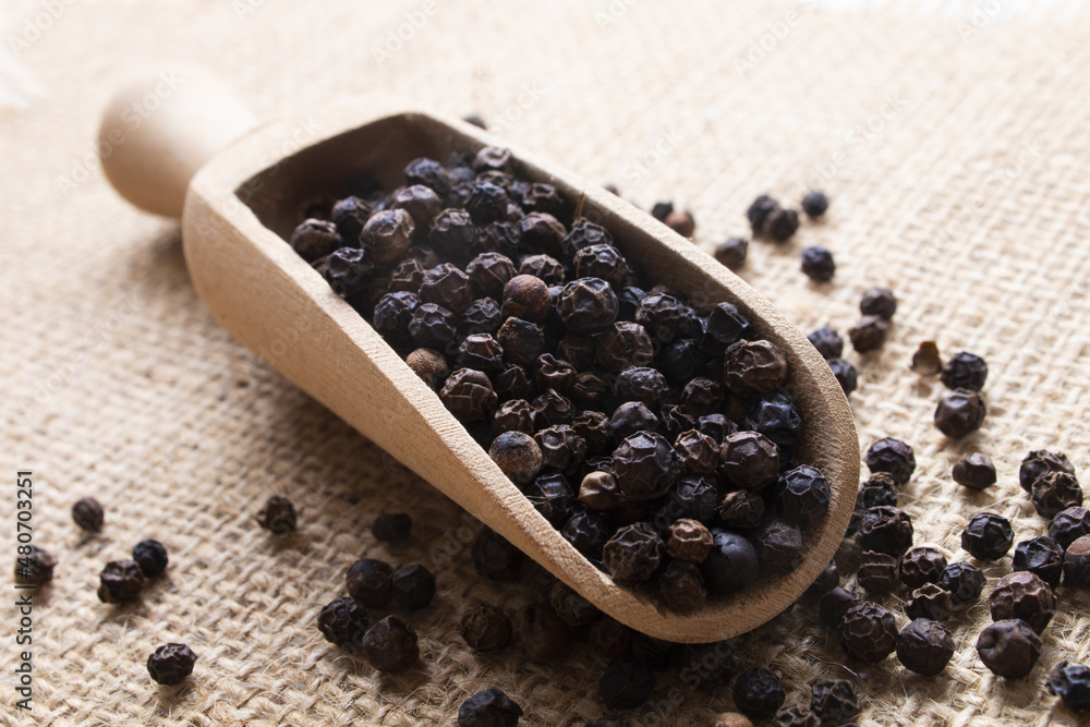 black peppercorns on a wooden scoop black peppercorns on a wooden scoop