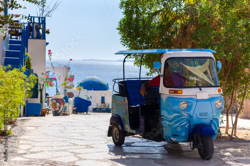 Traditional tuk-tuk moto taxi is waiting for passengers on empty road to sea at resort. Popular three-wheeler vehicle in Asian countries. High quality photo photo