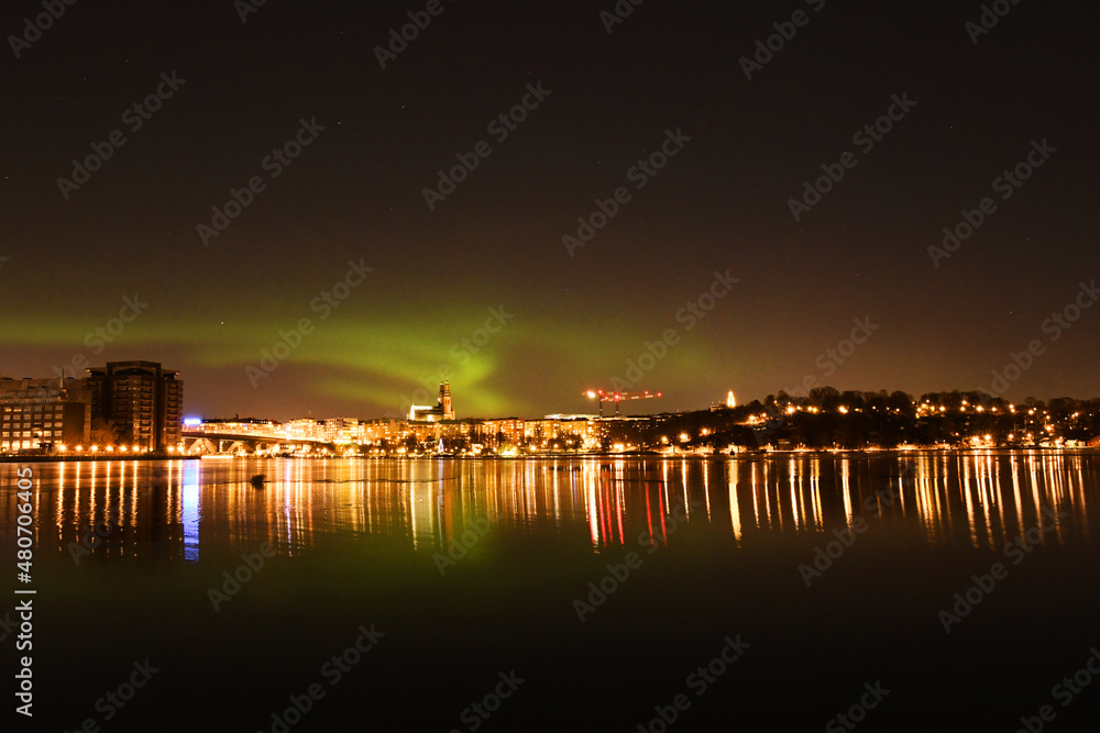 Northern lights, or Aurora Borealis, over Stockholm City skyline on a winter night. Night view of Södermalm in Stockholm, Sweden when northern lights is displayed. Photo taken January 15, 2022.
