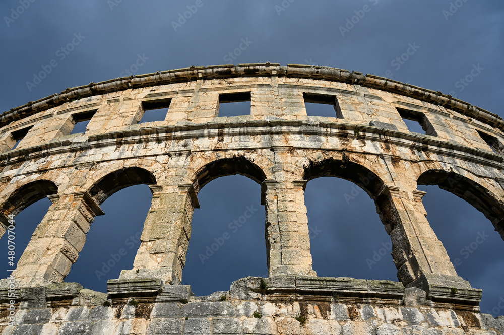 Pula, Istria, Croatia: Ancient amphitheater from Roman era in city centre. Monument against dark and dramatic clouds. Cultural heritage and famous landmark. Pulska Arena