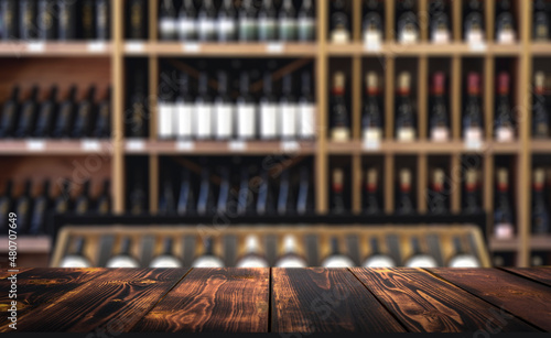 Wine wooden table background. Blurred wine shop with bottles on the counter. photo