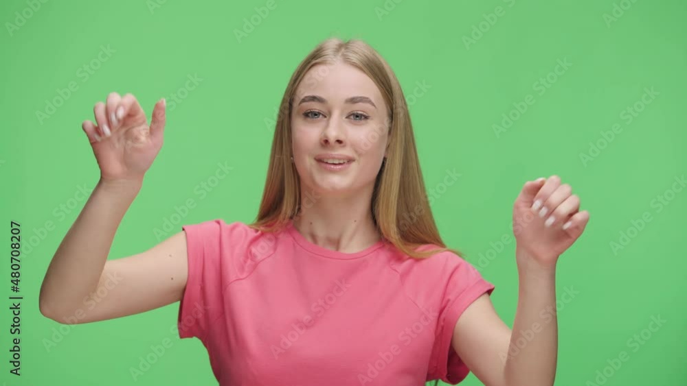 Portrait of an excited young girl banging her fists on glass, waving, calling someone and gesturing I am here. Model girl posing in studio against background of green screen. Close up. Slow motion. Portrait of an excited young girl banging her fists on glass, waving, calling someone and gesturing I am here. Model girl posing in studio against background of green screen. Close up. Slow motion.