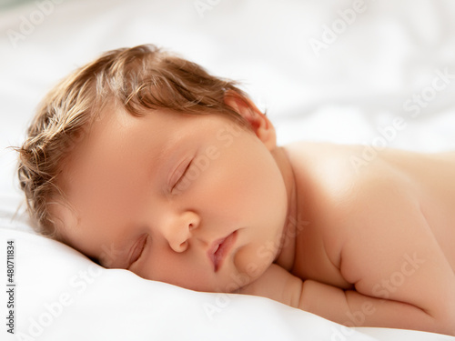 A Baby girl with Smily Face During Sleep. Little baby girl sleeping on white blanket. Beautiful portrait of little child girl 14 days, two weeks old. Motherhood