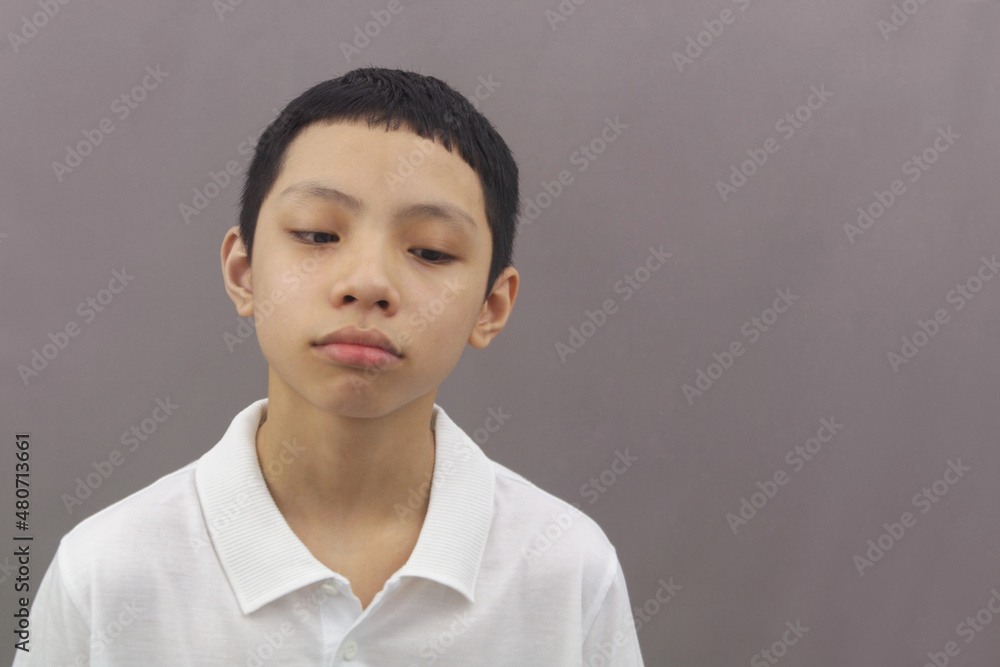 Sad and boring Asian boy on gray background. Copy space for text. Sad and boring Asian boy on gray background. Copy space for text.