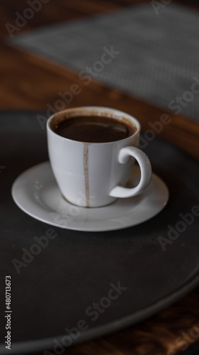 a mug of coffee stands on a tray in a restaurant. dark colors, loft style interior. no people