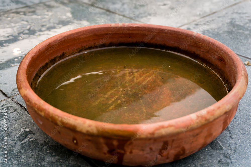 A close up shot of a wide mouth circular clay pot holding water.