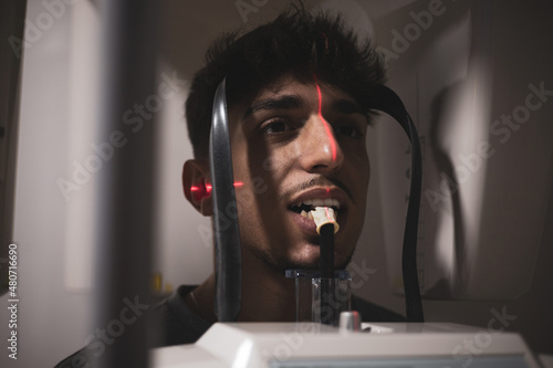 A man with Arab features undergoes a panoramic X-ray machine in a dental clinic.Cephalometric radiography system. photo