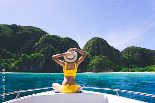 Rear view of adult traveling woman relax on the sailing boat with summer island and sea