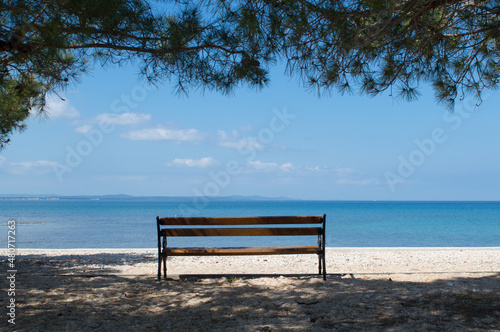 Empty wooden bench with the relaxing view on the blue Adriatic sea, tranquil scene in Zadar, Croatia