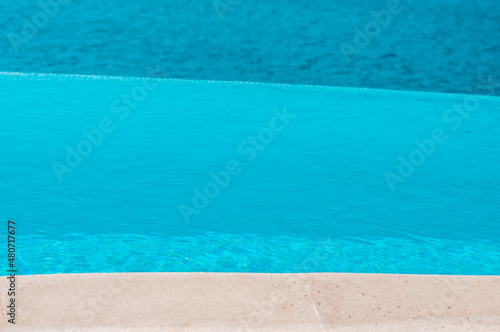 Summer vacation at poolside. Infinity swimming pool with sea on bright summer day