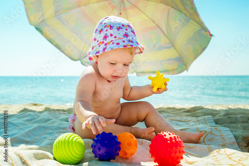 The baby is playing on the beach. Child at sea. Toys for sand and water. Sun protection for young children.