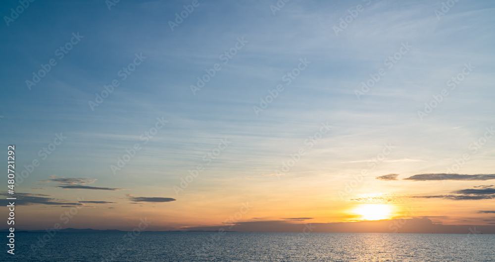 Sunset sky clouds over sea in the evening with orange sunlight golden hour, dusk sky 