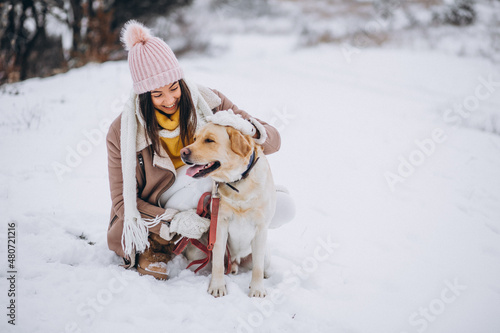 Fototapeta Naklejka Na Ścianę i Meble -  Young woman walking with her dog in a winter park