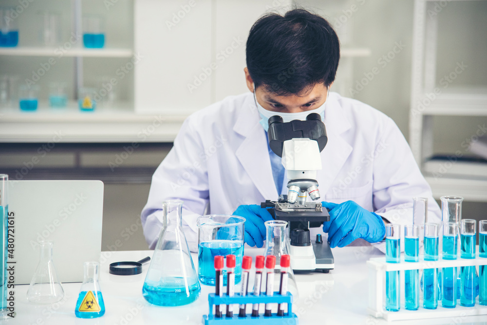 Scientist man look into Microscope research in science laboratory. Asian scientist looking equipment laboratory chemistry labs. Covid-19 coronavirus biochemistry research experiment vaccine concept Scientist man look into Microscope research in science laboratory. Asian scientist looking equipment laboratory chemistry labs. Covid-19 coronavirus biochemistry research experiment vaccine concept