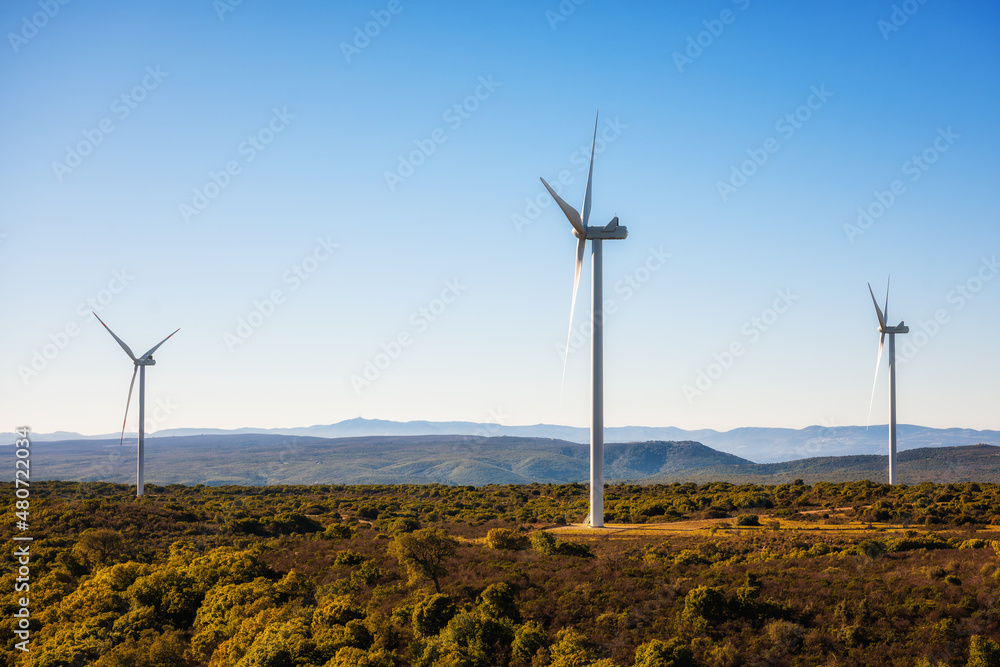 Obraz premium Wind turbines on a beautiful blue sky in a mountain wind farm in Sardinia. Renewable energy concept, green energy generation. Energy industry.