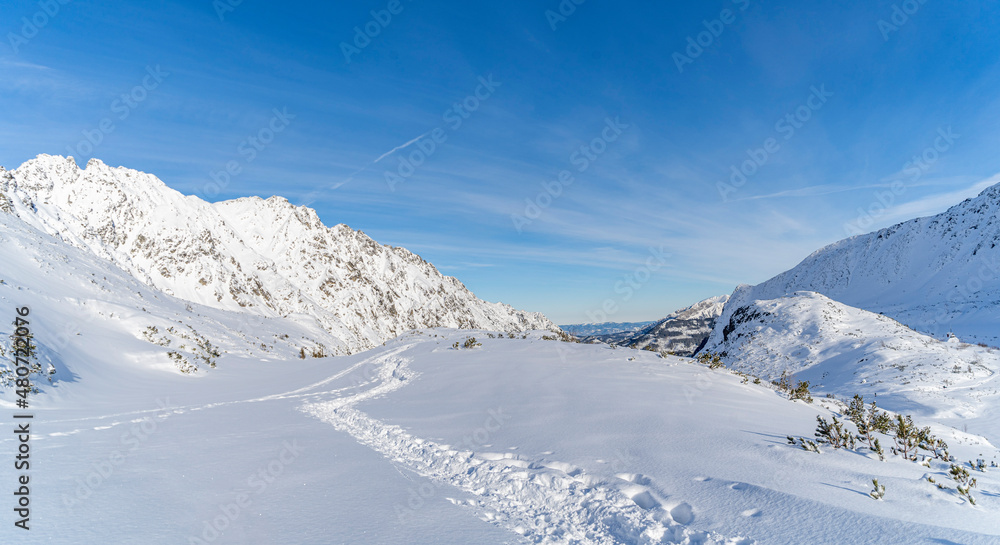 Mountain winter landscape in the Tatras, trail trampled in the snow overlooking the snow-capped mountains in frosty sunny weather Tatras Poland