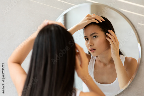 Quadro em tela Upset long-haired japanese woman checking her hair